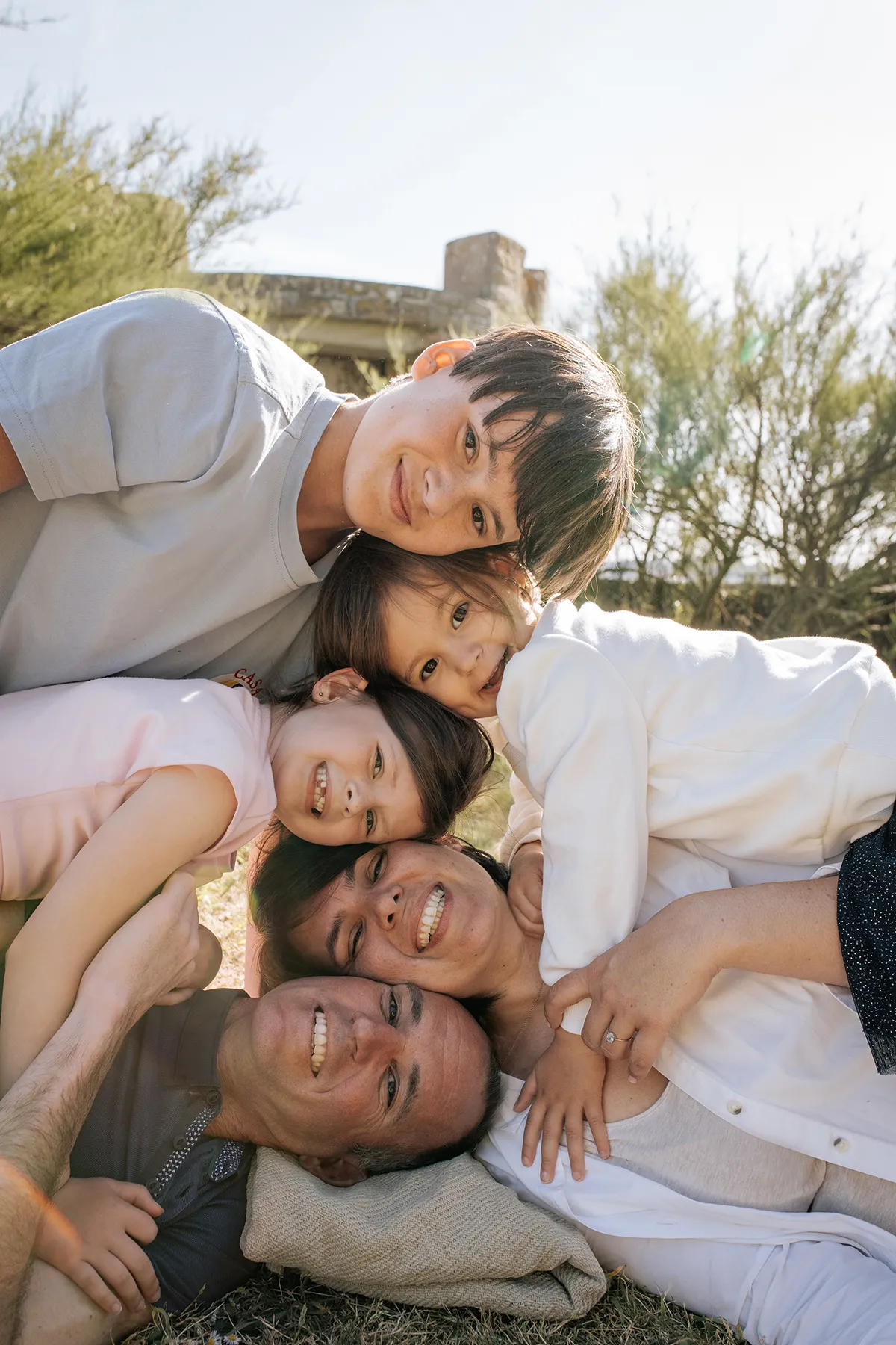 Famille allongée dans l'herbe pendant une séance photo naturelle