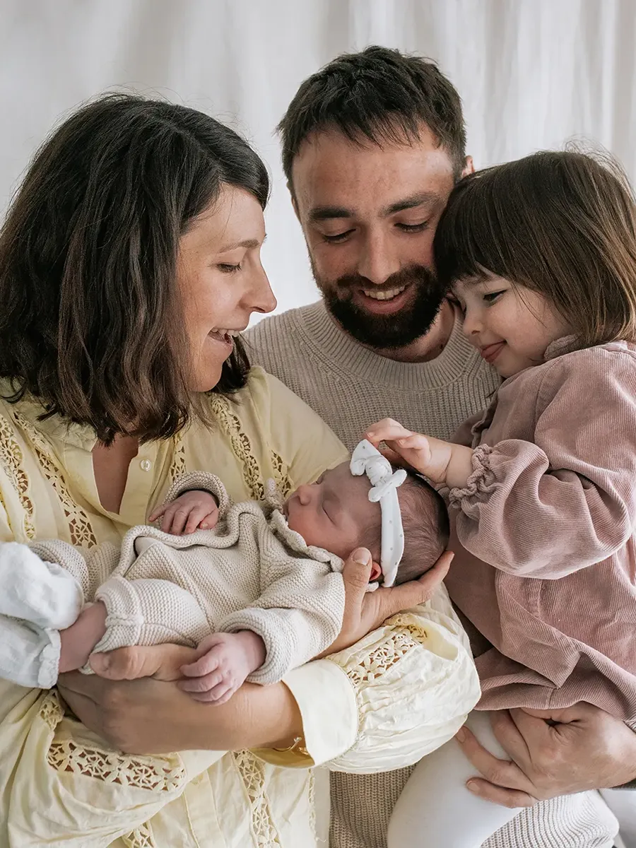 Nouveau-né photographié simplement dans les bras de ses parents au studio